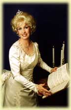 Woman in a vintage white gown holding sheet music beside candles.